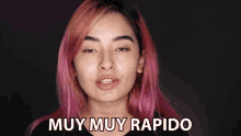 a woman with pink hair says muy muy rapido in front of her face