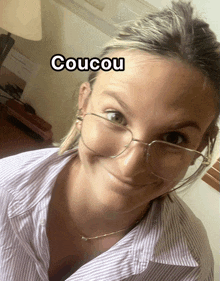 a woman wearing glasses and a striped shirt has the word coucou on her face