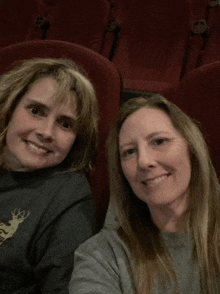 two women are sitting in a theater and one has a deer on her shirt