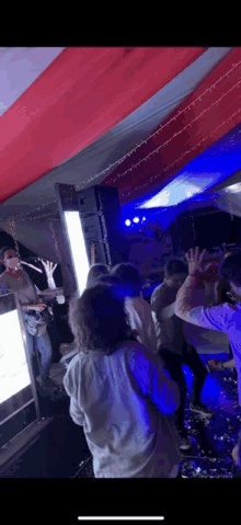 a group of people are dancing in a dark room with a man playing a guitar