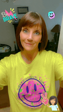 a woman is wearing a yellow shirt with a pink smiley face on it