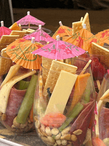 a variety of snacks in glasses with pink umbrellas on top