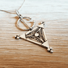 a silver necklace with a triangle shaped pendant