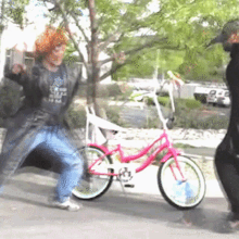 a man wearing a t-shirt that says ' texas ' on it is dancing in front of a pink bike