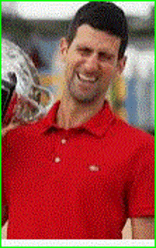 a man in a red shirt is smiling while holding a trophy