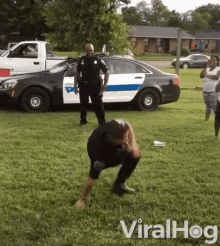 a police officer is kneeling down in front of a police car with the words viralhog written on the bottom