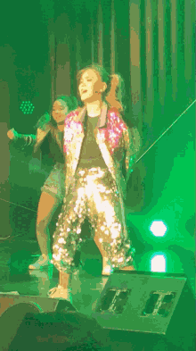 a woman in a sequined jacket and pants is dancing on stage