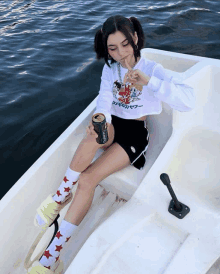 a girl sitting in a boat holding a can that says energy drink