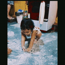 a little girl wearing a shirt that says ' coca cola ' on it is playing with flour on the floor