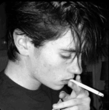 a young man smoking a cigarette in a black and white photo