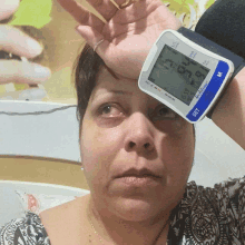 a woman holds her hand to her forehead while wearing a wrist blood pressure monitor that says " set "