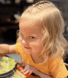 a little girl is sitting at a table looking at a menu