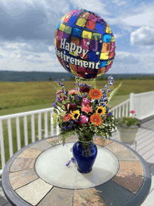 a vase of flowers sits on a table with a balloon that says happy retirement