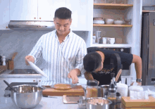 two men are preparing food in a kitchen and one of them is wearing a shirt that says ' i love you ' on it