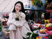 a woman in a white coat is kneeling down holding flowers