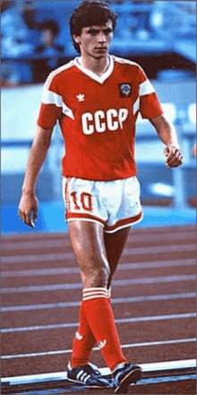 a man wearing a red cccp jersey and shorts walks on a track