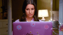 a woman is using a purple laptop with flowers on the cover