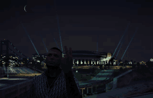 a man stands in front of a stadium at night