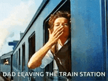 a woman is covering her mouth while looking out of a train window with the caption dad leaving the train station .