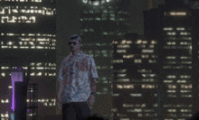 a man in a hawaiian shirt stands in front of a city skyline