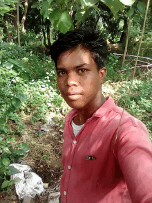 a young man taking a selfie in the woods wearing a red shirt that says ' lg ' on the pocket