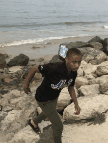 a boy wearing a black shirt that says mets is running on rocks