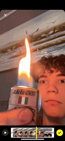 a young man is holding a zippo lighter with a flame on it