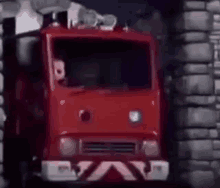 a red fire truck is parked next to a brick wall .