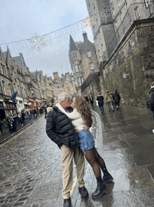 a man and a woman are kissing on the sidewalk