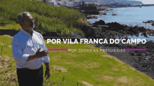 a man stands on a hill overlooking the ocean with the words por vila franca do campo