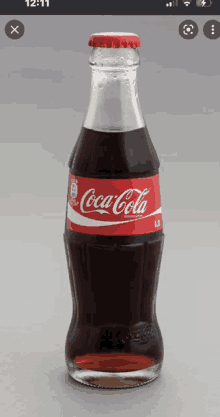 a bottle of coca cola is sitting on a gray surface