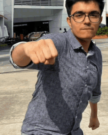 a man wearing glasses and a blue shirt is giving a fist bump in front of a starbucks coffee store