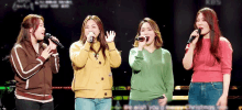 a group of women singing into microphones on a stage in front of a kbs logo