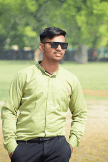 a man wearing sunglasses and a green shirt stands in a field