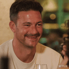 a man is smiling and holding a wine glass with netflix written on the bottom right