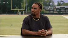 a man sits at a table with his hands folded in front of a field with the word boston on the bottom