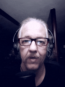 a man with glasses and a mustache wearing headphones and a microphone