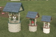 three wishing wells with blue roofs are sitting in a grassy field