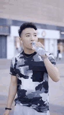 a young man is drinking water from a bottle while wearing headphones .