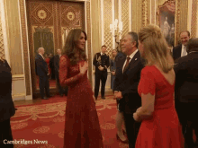 a woman in a red dress is talking to a man in a suit with cambridges news written on the bottom right