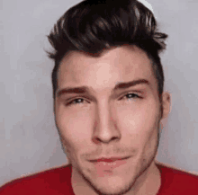 a close up of a man 's face with a red shirt on and a hat on .