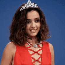 a woman wearing a red dress and a tiara smiles