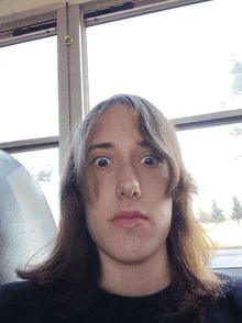 a woman with long hair making a funny face in front of a window