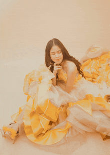 a woman in a yellow and white dress is sitting on the floor