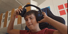 a young boy wearing headphones with a red shirt