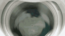 a washing machine is filled with water and clothes are being washed in it .