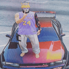 a man wearing a purple lakers jersey is standing on top of a car