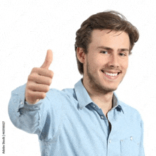 a young man in a blue shirt is giving a thumbs up sign