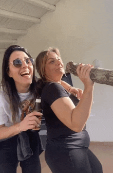 two women laughing and one is holding a log