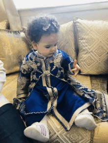 a little girl sitting on a couch wearing a blue dress